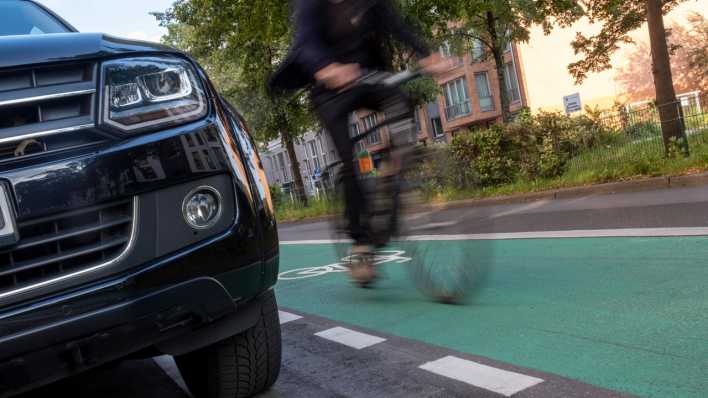 Fahrradfahrer und die Front eines massiven SUVs