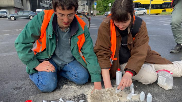 Demonstranten der "Letzten Generation" Markus und Hannah kleben sich in Berlin auf der Straße fest