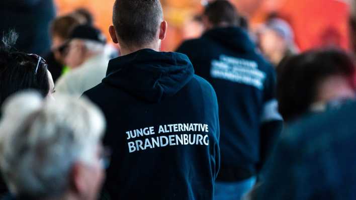 Teilnehmer einer Wahlkampfveranstaltung tragen Kleidung mit der Aufschrift "Junge Alternative Brandenburg".