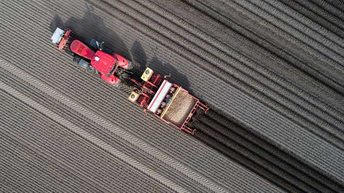 Eine Drohnenaufnahme zeigt einen Traktor, der mit Hilfe von GPS Kartoffeln aussät.