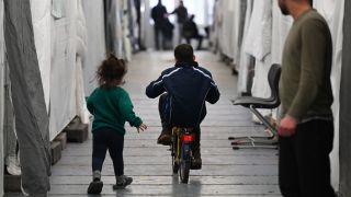 Flüchtlinge sind in einem Zelt einer provisorischen Flüchtlingsunterkunft unterweg