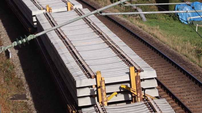 Blick auf einen vorbeifahrenden Güterzug mit Eisenbahnschwellen