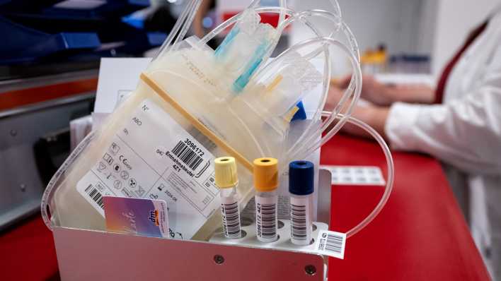 Ein leerer Beutel und Teströhrchen stehen beim Blutspendedienst des Bayerischen Roten Kreuzes vor einer Blutspende auf einem Tisch.