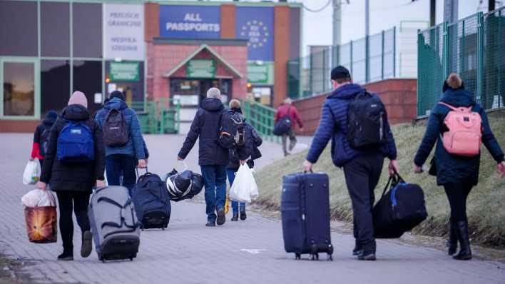 Menschen mit Gepäck passieren eine EU-Außengrenze.