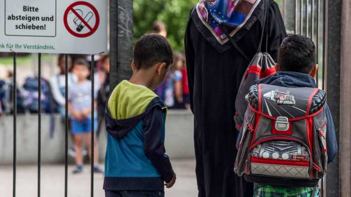 Symbolbild: Kinder gehen mit ihrer Mutter auf den Schulhof