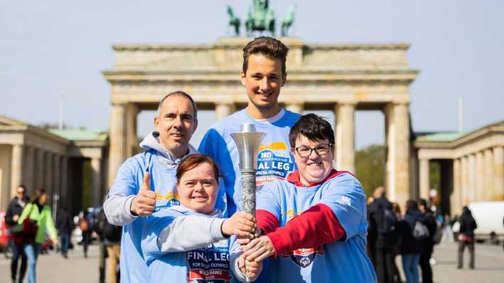 28.4.23: Nicole Pietschmann (vorne l-r), Schwimmerin, Juliana Rößler, Kanutin und Athletenspecherin, Marko Fähling (hinten l-r), Leichtathlet, und Louis Kleemeyer, Tennisspieler und Mitglied des Organisationskomitees, halten die Fackel für die Special Olympics World Games, als diese am Brandenburger Tor vorgestellt wird (Bild: picture alliance/dpa)