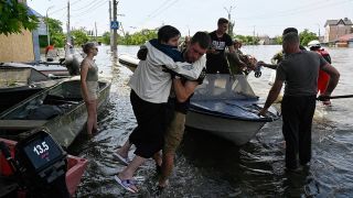 Retter helfen im Überschwemmungsgebiet in der ukrainischen Region Cherson einer Frau von einem Boot, an Land zu kommen.
