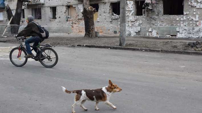 Ein Mann fährt an einem durch Beschuss beschädigten Gebäude in Orichiw vorbei