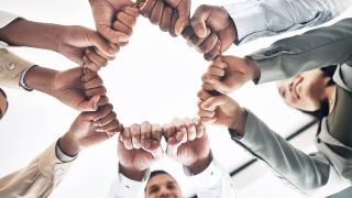 Junges Team streckt die Hände zusammen