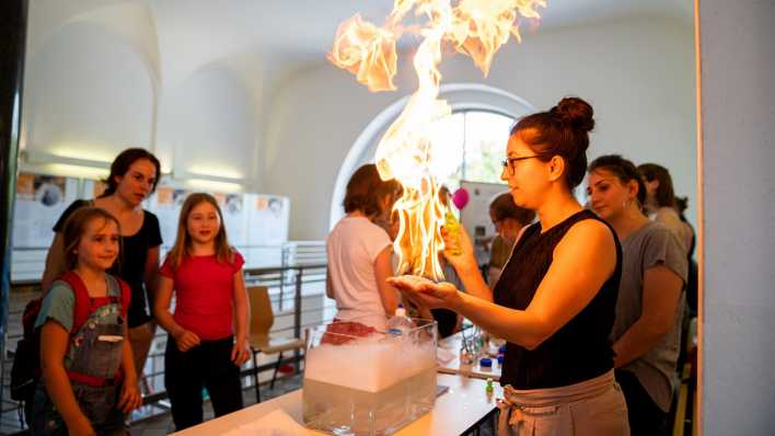 Eine Wissenschaftlerin zeigt ein Chemieexperiment an der Technischen Universität Berlin.