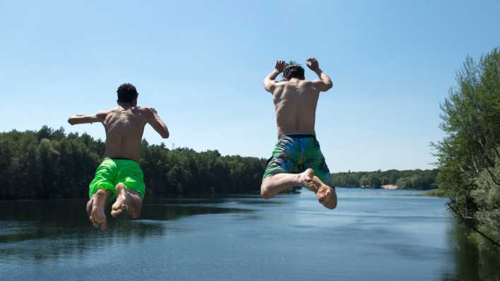Zwei Männer springen in den Flughafensee in Berlin-Tegel.
