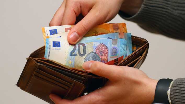 Eine Frau zählt ihre Geldscheine ihrem Portemonnaie.