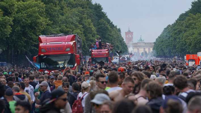 Die Techno-Parade "Rave the Planet" zieht im Juni 2022 durch Berlin - im Hintergrund sind Brandenburger Tor und Rotes Rathaus zu sehen.