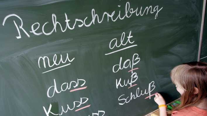 Eine Schülerin einer Grundschule schreibt die jeweils neuen und alten Schreibweisen von Wörtern an eine Tafel.