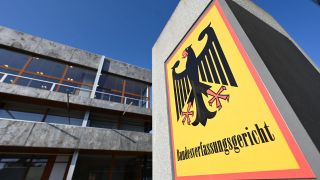 Vor dem Bundesverfassungsgericht hängt ein Hinweisschild mit der Aufschrift Bundesverfassungsgericht und dem Bundesadler.