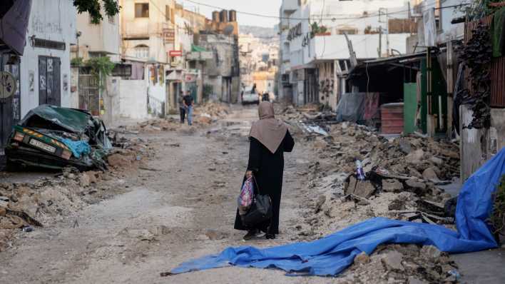 Eine palästinensische Frau geht zwischen Trümmern, nach einer groß angelegten Militäroperation des israelischen Militärs in Dschenin im Westjordanland (Bild: dpa / Majdi Mohammed)