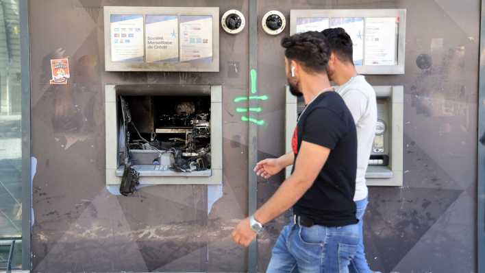 Zwei junge Männer laufen in Marseille nach Krawallen in Frankreich an einem zerstörten Bankautomaten vorbei. (Bild: picture alliance/dpa)