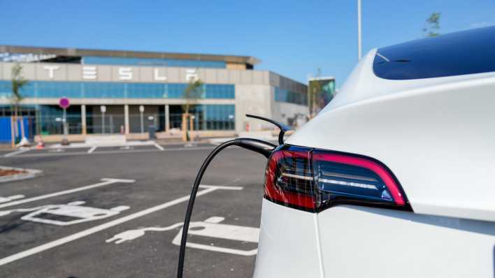 Ein weißer Tesla Model Y steht zum Laden auf dem E-Parkplatz der Tesla Gigafactory in Grünheide (Bild: picture alliance / SULUPRESS.DE).