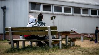 Zwei Asylsuchende in der Erstaufnahmeeinrichtung Eisenhüttenstadt sitzen auf einer Bank.