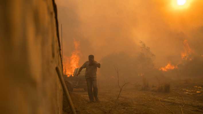 Ein Einheimischer flieht vor den Flammen von einem Waldbrand im Dorf Gennadi. in Griechenland (Bild: dpa)