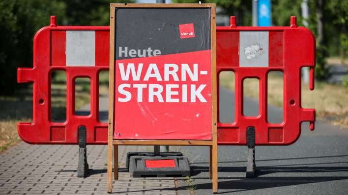 Ein Schild mit der Aufschrift "Heute Warnstreik" steht auf einem Gehweg (Bild: dpa / Jan Woitas)