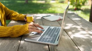 Eine Frau sitzt im Garten an ihrem Laptop.