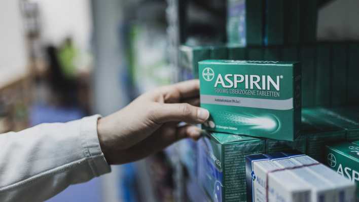 Apotheker nimmt eine Packung Aspirin aus einem Schrank