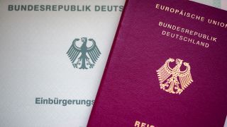 Eine Einbürgerungsurkunde der Bundesrepublik Deutschland (l) und ein deutscher Reisepass liegen auf einem Tisch