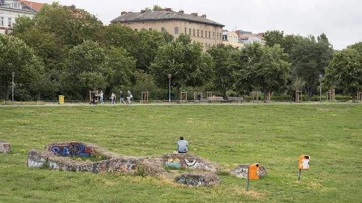 Ein Mann sitzt im Görlitzer Park auf Steinen.