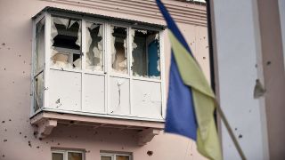 Ein durch russischen Beschuss zerstörter Balkon ist in Isjum hinter einer ukrainischen Flagge zu sehen.