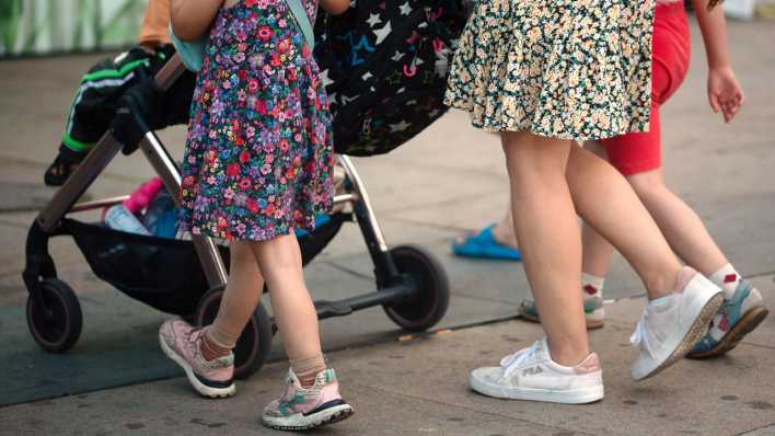 Eine Frau schiebt einen Kinderwagen und geht begleitet von mehreren Kindern. (Bild: dpa)