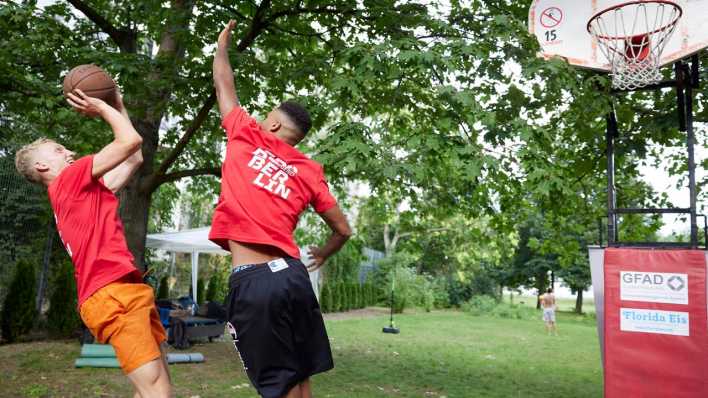 Die Übungsleiter Anselm (l) und Jess spielen im Rahmen eines Sportprojekts im Prinzenbad Basketball.