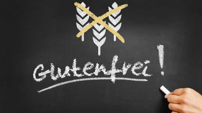 Hand schreibt glutenfrei mit Symbol von Getreide an eine Tafel