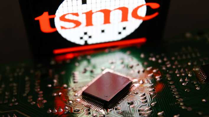 Hinter einem Mikrochip ist das Logo des taiwanischen Unternehmens TSCM auf einem Smartphone zu sehen. (Fotomontage)