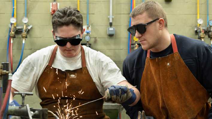 Auszubildender im Beruf Metallbauer wird von seinem Meister im Schweissen unterrichtet