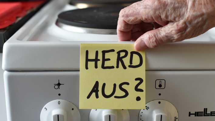Ein Klebezettel mit dem Schriftzug "Herd aus?" klebt an einem Herd neben den Drehknöpfen.