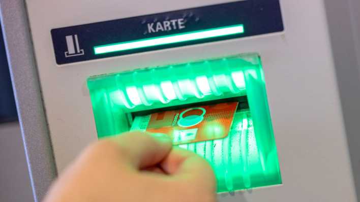 Eine Bankkundin steckt ihre Girokarte in einen Geldautomaten