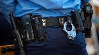 Handschellen und eine Dienstwaffe sind an dem Gürtel eines Polizisten befestigt