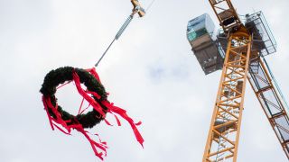 Ein Kranz hängt beim Richtfest vor einem Neubauprojekt