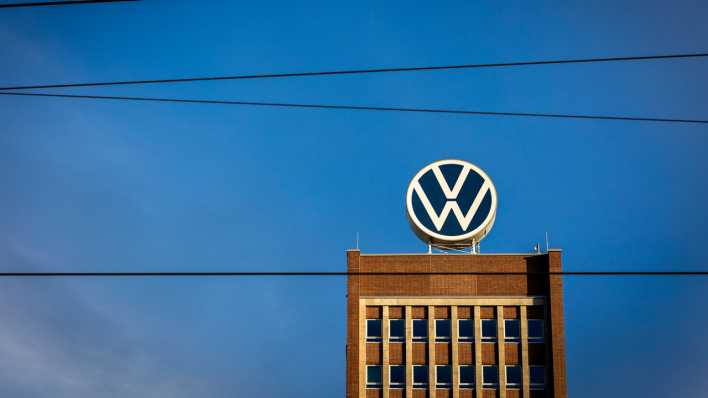 Das Markenhochhaus im Volkswagen Stammwerk ist am Morgen hinter Leitungen einer Bahnstrecke zu sehen.