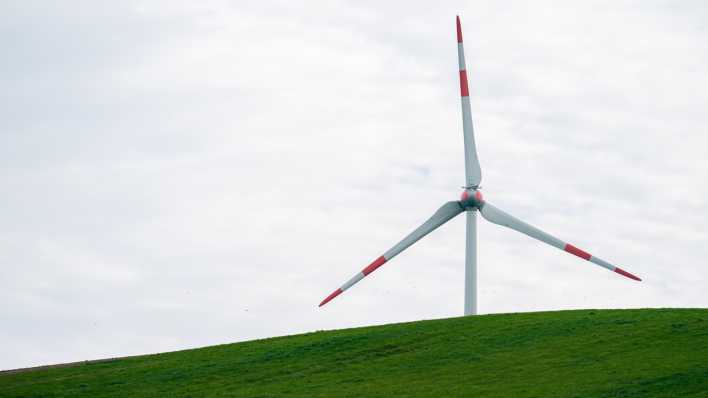 Leichte Wolken ziehen über Windräder hinweg.