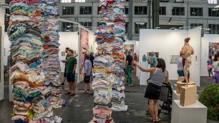 Besucherinnen und Besucher betrachten Kunst auf der Positions Kunstmesse in Berlin-Tempelhof.