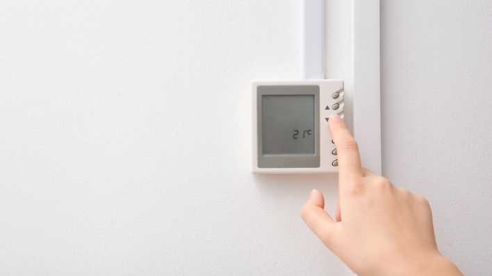 Frau stellt Thermostat ein