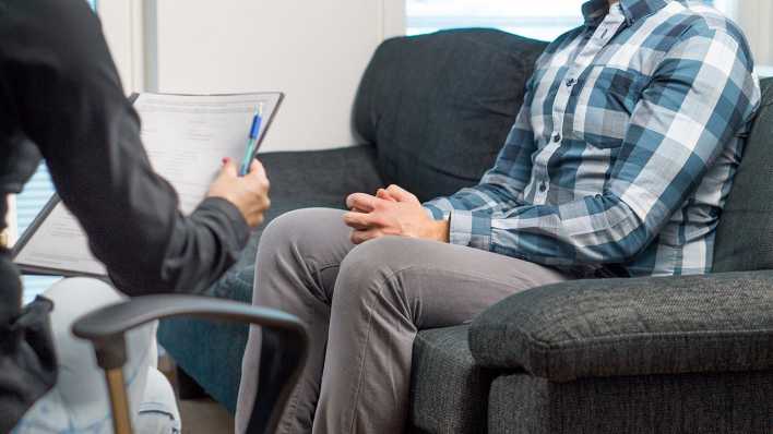 Eine Psychotherapeutin spricht mit einem Patienten.