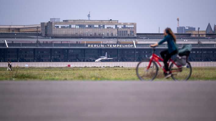 Eine Fahrradfahrerin fährt über das Rollfeld auf dem Gelände des ehemaligen Flughafens Berlin-Tempelhof.