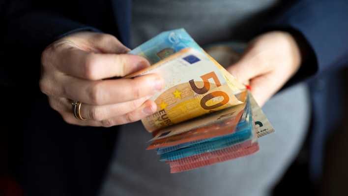 Eine Frau hält mehrere Euro-Scheine in der Hand.