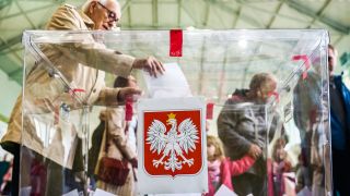 Ein Mann wirft seinen Stimmzettel in eine Urne bei der Wahl in Polen.