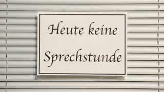 Ein Schild mit der Aufschrift "Heute keine Sprechstunde" hängt im Fenster einer Arztpraxis vor einer Jalousie. (Bild: Sebastian Kahnert/dpa-Zentralbild/dpa)
