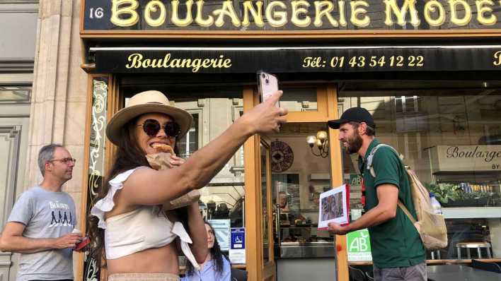 Amerikaneri posiert eine Szene aus "Emily in Paris" nach und knipst ein Selfie (Bild: picture alliance/dpa/MAXPPP/Sofia Mazhar)