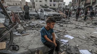 Ein palästinensischer Junge sitzt mitten im Schutt eines zerstörten Gebäudes (Bild: picture alliance/dpa | Abed Rahim Khatib)